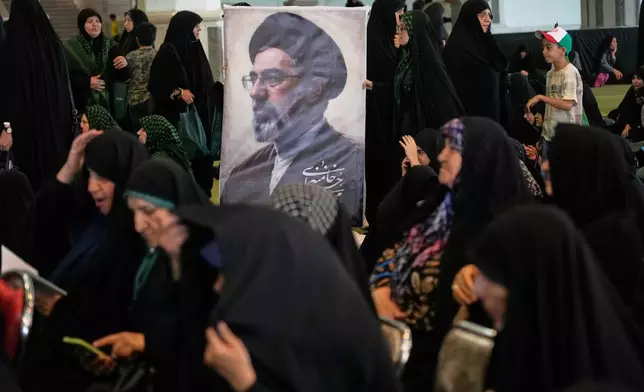 Women gather around a portrait of Iran's Supreme Leader, Ayatollah Mojtaba Khamenei, during a ceremony honoring the armed forces and those killed in the war with Israel and the U.S. at the Imam Khomeini Grand Mosque in Tehran, Iran, Sunday, May 24, 2026. (AP Photo/Vahid Salemi)