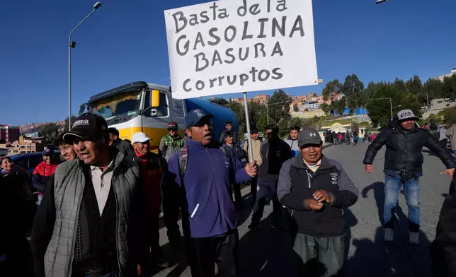 FILE - Public transport drivers protest poor gasoline fuel quality, one holding a sign with a message that reads in Spanish; "Enough with the trash gas. Corrupt ones," in La Paz, Bolivia, March 25, 2026. (AP Photo/Juan Karita, File)