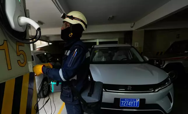 An electrician installs a home electric vehicle charging station in La Paz, Bolivia, Tuesday, April 21, 2026. (AP Photo/Juan Karita)
