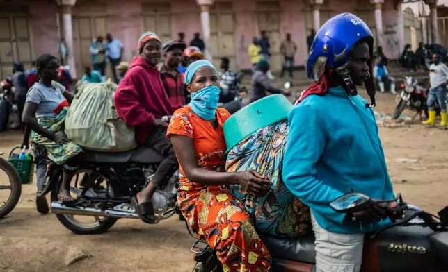 Motorcycle taxi riders and their passengers wait at the entrance to the central market while sanitation workers disinfect the area, as Ituri province continues to combat an Ebola outbreak in Bunia, Congo, Saturday, May 23, 2026. (AP Photo/Moses Sawasawa)