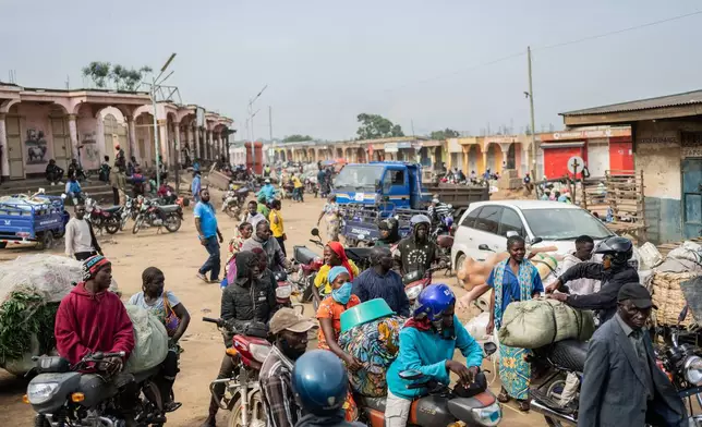 Motorcycle taxi riders and their passengers wait at the entrance to the central market while sanitation workers disinfect the area, as Ituri province continues to combat an Ebola outbreak in Bunia, Congo, Saturday, May 23, 2026. (AP Photo/Moses Sawasawa)