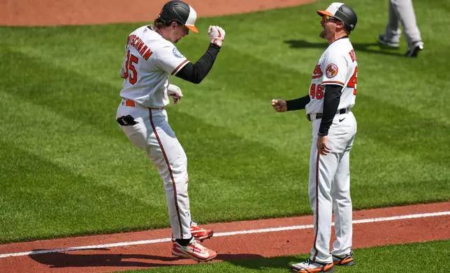 Baltimore Orioles' Adley Rutschman (35) celebrates with third base coach Buck Britton (46) after hitting a grand slam during the fifth inning in the first baseball game of a doubleheader against the Houston Astros, Thursday, April 30, 2026, in Baltimore. (AP Photo/Stephanie Scarbrough)