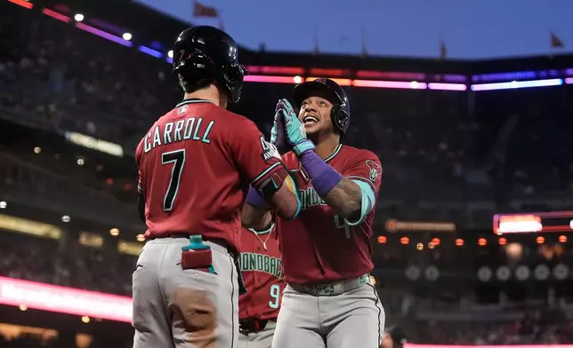Arizona Diamondbacks' Ketel Marte, right, is congratulated by Corbin Carroll (7) after hitting a two-run home run that also scored Tommy Troy, rear, during the seventh inning of a baseball game against the San Francisco Giants Tuesday, May 26, 2026, in San Francisco. (AP Photo/Jeff Chiu)