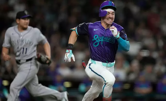 Arizona Diamondbacks' Corbin Carroll (7) runs past Colorado Rockies starting pitcher Tomoyuki Sugano (11), of Japan, as Carroll beats out an infield single during the fifth inning of a baseball game, Friday, May 22, 2026, in Phoenix. (AP Photo/Ross D. Franklin)