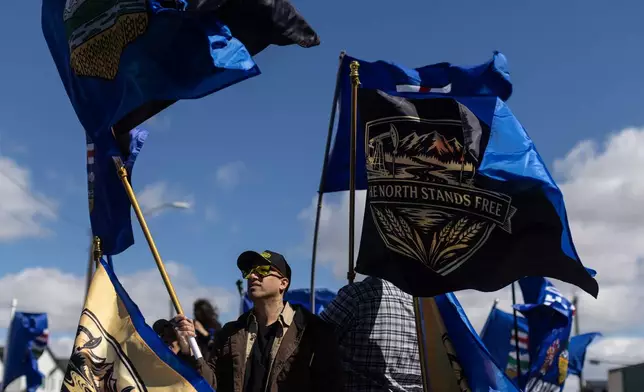 Supporters fly flags in support of Mitch Sylvestre as he submits his signatures for a separation referendum to Elections Alberta in Edmonton, on Monday, May 4, 2026. (Jason Franson/The Canadian Press via AP)