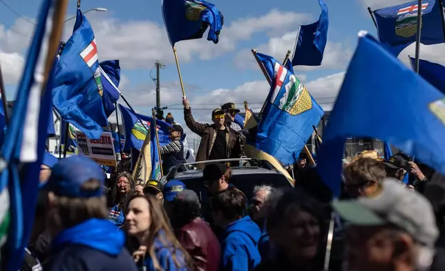 Supporters fly flags in support of Mitch Sylvestre as he submits his signatures for a separation referendum to Elections Alberta in Edmonton, on Monday, May 4, 2026. (Jason Franson/The Canadian Press via AP)