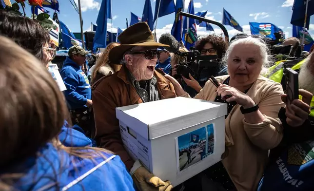 Supporters carry boxes of signatures to submit for a separation referendum to Elections Alberta in Edmonton, on Monday, May 4, 2026. (Jason Franson/The Canadian Press via AP)