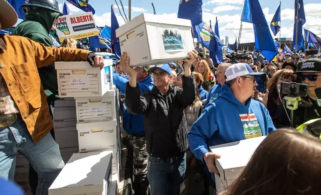 Supporters carry boxes of signatures to submit for a separation referendum to Elections Alberta in Edmonton, on Monday, May 4, 2026. (Jason Franson/The Canadian Press via AP)
