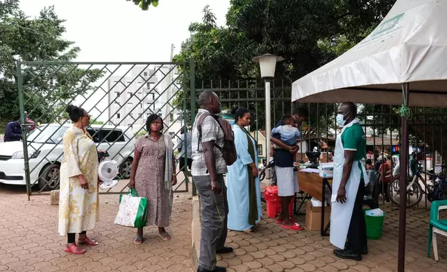People wait to have their temperature taken in front of Kibuli Muslim Hospital in Kampala, Uganda, Saturday, May 16, 2026. (AP Photo/ Hajarah Nalwadda)