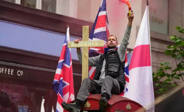 A protester sits on a phone box during the far right Unite the Kingdom march in London, Saturday, May 16, 2026.(AP Photo/Kirsty Wigglesworth)