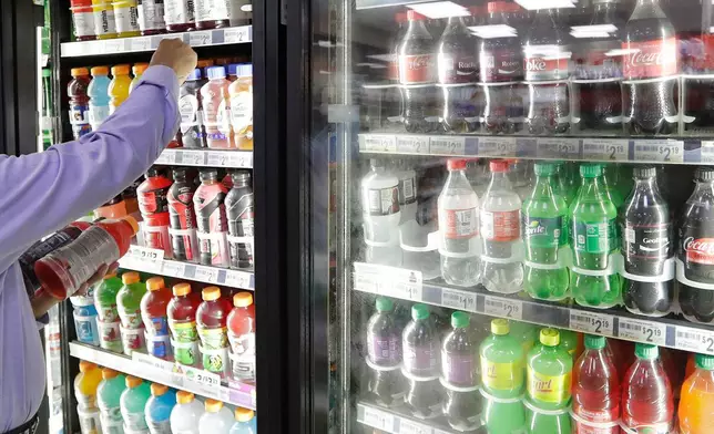 FILE - A shop owner reaches into a drink display refrigerator at his convenience store in Kent, Wash., Oct. 1, 2018. (AP Photo/Elaine Thompson, File)