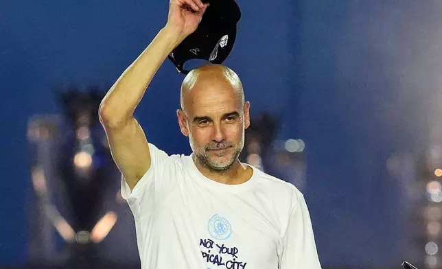 Manchester City manager Pep Guardiola raises his hat to the crowd during a stage event following a parade to celebrate the achievements of the Manchester City men's and women's teams this season in Manchester, England, Monday, May 25, 2026. (Nick Potts/PA via AP)