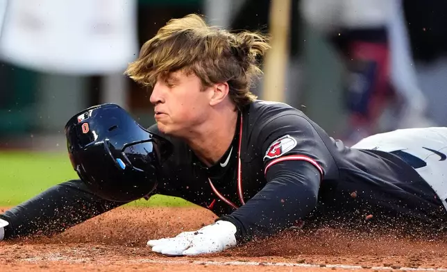 Cleveland Guardians' Petey Halpin slides home to score on a two-run single hit by Chase DeLauter during the fifth inning of a baseball game against the Kansas City Royals, Wednesday, May 6, 2026, in Kansas City, Mo. (AP Photo/Charlie Riedel)