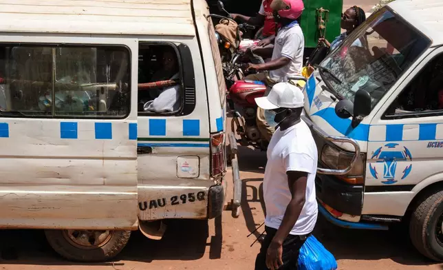A man wearing a protective mask walks along a busy street in Kampala, Uganda, Tuesday, May 19, 2026. (AP Photo/Hajarah Nalwadda)