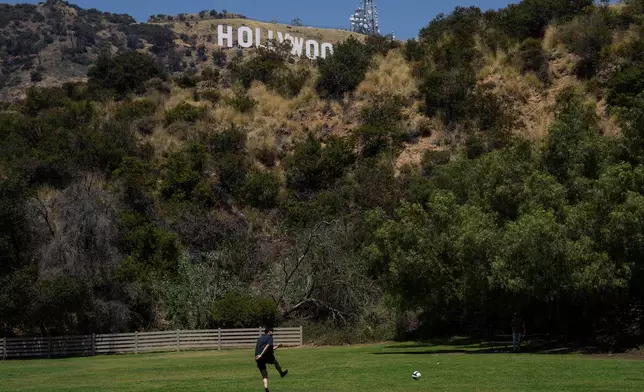 A person kicks a soccer ball in a park beneath the Hollywood sign in Los Angeles, May 8, 2026. (AP Photo/Jae C. Hong)