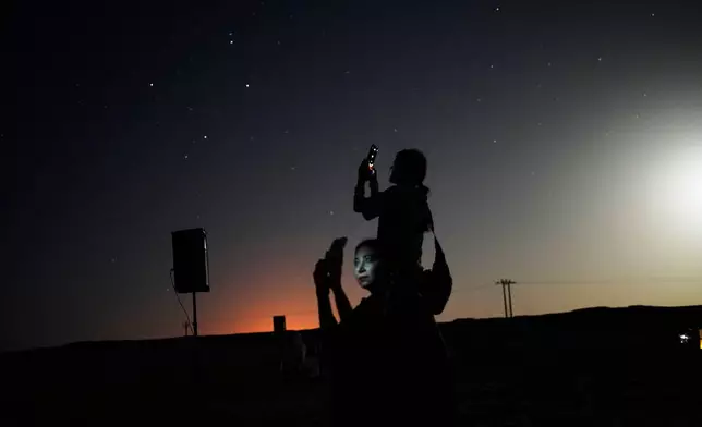 This long-exposure photograph shows women taking mobile phone pictures in the Al Quaa Desert outside of Abu Dhabi, United Arab Emirates, Saturday, May 23, 2026. (AP Photo/Jon Gambrell)
