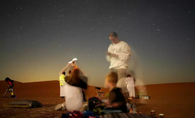 This long-exposure photograph shows a family taking mobile phone pictures in the Al Quaa Desert outside of Abu Dhabi, United Arab Emirates, Saturday, May 23, 2026. (AP Photo/Jon Gambrell)