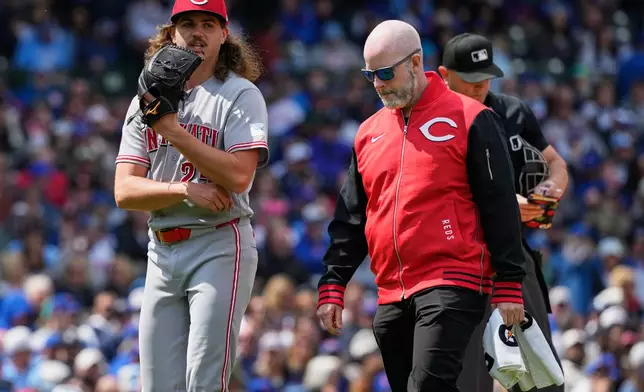 Cincinnati Reds starting pitcher Rhett Lowder, left, leaves as he talks with a team trainer after an injury during the fourth inning of a baseball game against the Chicago Cubs in Chicago, Thursday, May 7, 2026. (AP Photo/Nam Y. Huh)