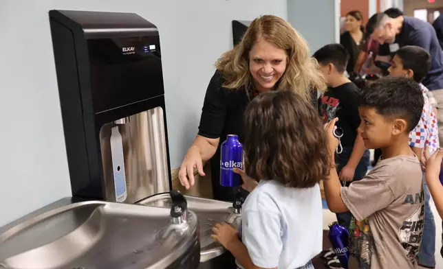 Angela Hersil, Zurn Elkay VP - Public Affairs and Sustainability, helps second-graders Madelyn Gonzalez-Garcia and Sebastian Garcia fill their bottles at the new Elkay Pro Filtration bottle filling station at Dalton Elementary School in Uvalde, TX.