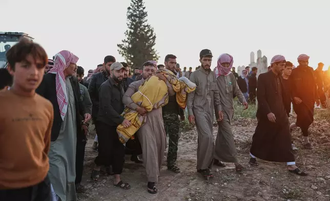 Idris Al-Ridah carries the body of his son Amir killed by an explosion caused by war remnants while he was playing with other children in the village of Abu Habbah in eastern Idlib countryside, during his funeral in Abu Habbah, Syria, Thursday, May 21, 2026. Two other children were also killed and four others were wounded.(AP Photo/Ghaith Alsayed)