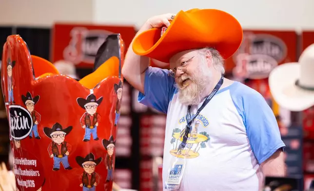 Shareholder Alex Vacca of Milwaukee poses for a photo in a foam hat in the Justin display od the Berkshire Hathaway annual meeting on Saturday, May 2, 2026, in Omaha, Neb. (AP Photo/Rebecca S. Gratz)