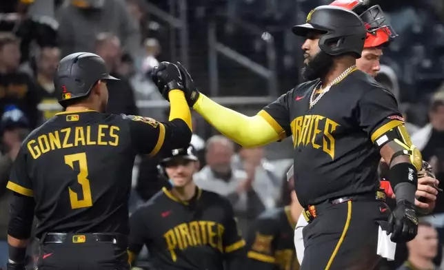 Pittsburgh Pirates' Marcell Ozuna celebrates with Nick Gonzales (3) on his way back to the dugout after his two run home run off of Cincinnati Reds pitcher Zach Maxwell in the fifth inning of a baseball game in Pittsburgh, Friday, May 1, 2026. (AP Photo/Tom E. Puskar)