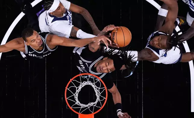 San Antonio Spurs forward Victor Wembanyama (1) and guard Stephon Castle (5) battle Minnesota Timberwolves forward Jaden McDaniels, center, and guard Ayo Dosunmu, right, for a rebound during the first half of Game 5 of an NBA basketball second-round playoffs series in Minneapolis, Tuesday, May 12, 2026. (AP Photo/Eric Gay)