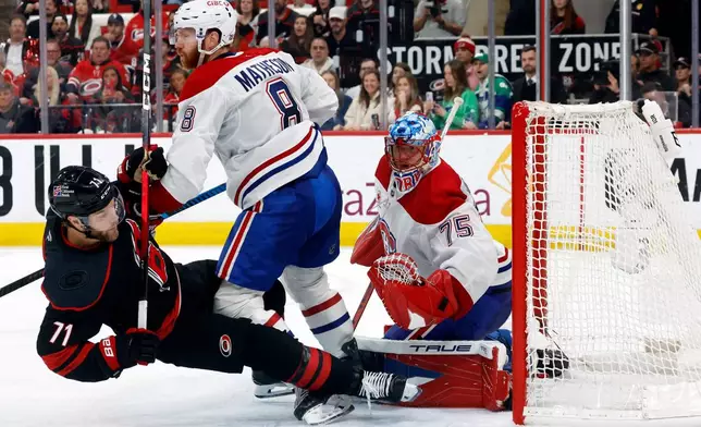 Montréal Canadiens' Mike Matheson (8) takes out Carolina Hurricanes' Taylor Hall (71) in front of Canadiens goaltender Jakub Dobes (75) during the second period in Game 1 of the Eastern Conference finals NHL hockey Stanley Cup playoffs series in Raleigh, N.C., Thursday, May 21, 2026. (AP Photo/Karl DeBlaker)