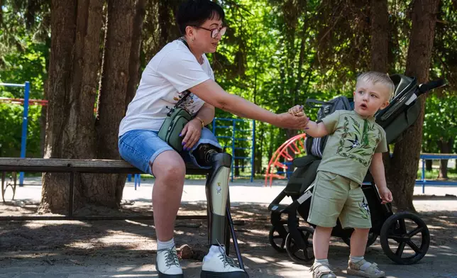 Iryna Nakonechna plays with her grandson Tymofii in a park of Kryvyi Rih, Ukraine, Saturday, May 9, 2026. (AP Photo/Evgeniy Maloletka)