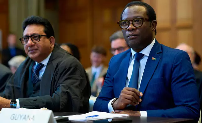 Guyana's Foreign Affairs minister Hugh Hilton Todd, right, and former Foreign Affairs minister Carl Greenidge, left, wait for the International Court of Justice to open a week of hearings in a border dispute dating back to the end of the 19th century between Guyana and Venezuela, in The Hague, Netherlands, Monday, May 4, 2026. (AP Photo/Peter Dejong)
