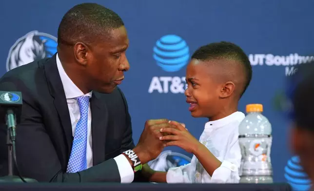 Dallas Mavericks' new team president Masai Ujiri, left, comforts his crying son Amani, 5, before starting an introductory NBA basketball news conference in Dallas, Tuesday, May 5, 2026. (AP Photo/LM Otero)