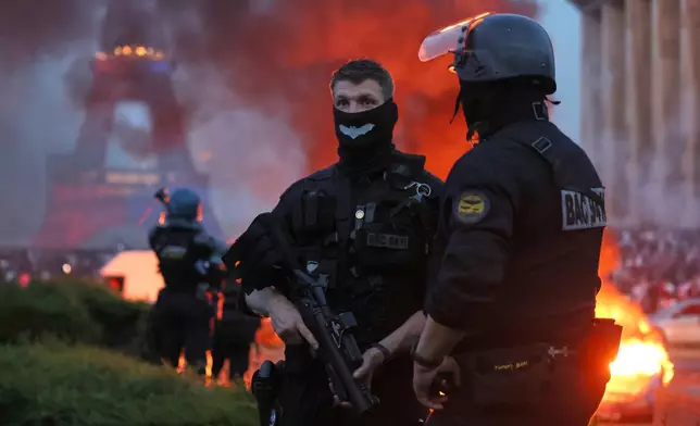 A car burns and fireworks explode as police watch PSG supporters celebrate in Paris, Saturday, May 30, 2026 after the Champions League final soccer match between Paris Saint-Germain and Arsenal that's being played in Budapest, PSG won the game. (AP Photo/Thomas Padilla)