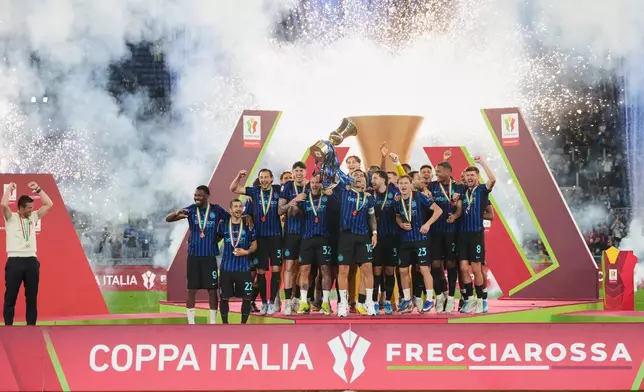 Inter Milan's team captain Lautaro Martinez lifts the trophy while Inter Milan head coach Cristian Chivu at left celebrates after defeating Lazio to win the Italian Cup soccer final in Rome, Wednesday, May 13, 2026. (AP Photo/Andrew Medichini)