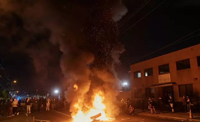 People watch a burning barricade near the Delaney Hall detention center during a protest against the transfer of detainees and federal immigration policies on Saturday, May 30, 2026, in Newark, N.J. (AP Photo/Andres Kudacki)
