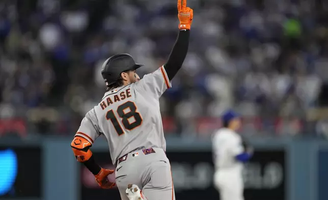 San Francisco Giants' Eric Haase, gestures as he rounds first after hitting a solo home run during the third inning of a baseball game against the Los Angeles Dodgers, Tuesday, May 12, 2026, in Los Angeles. (AP Photo/Mark J. Terrill)