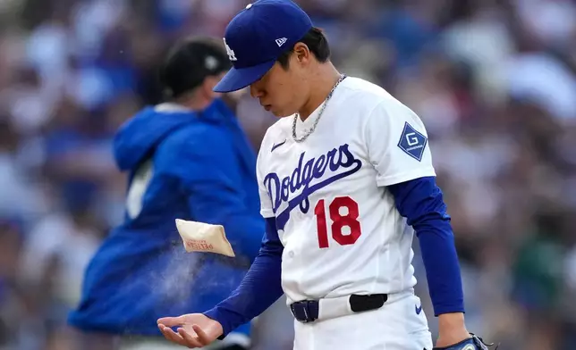 Los Angeles Dodgers pitcher Yoshinobu Yamamoto picks up a rosin bag prior to the first inning of a baseball game against the San Francisco Giants, Tuesday, May 12, 2026, in Los Angeles. (AP Photo/Mark J. Terrill)
