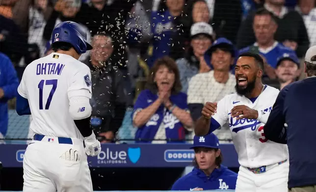 Los Angeles Dodgers' Shohei Ohtani, left, has seeds thrown at him by Teoscar Hernández after hitting a solo home run during the third inning of a baseball game against the San Francisco Giants, Tuesday, May 12, 2026, in Los Angeles. (AP Photo/Mark J. Terrill)