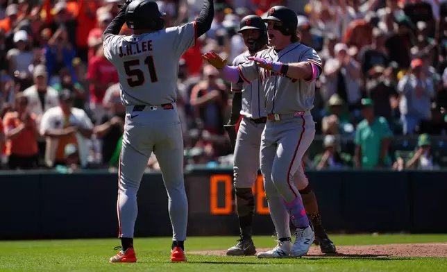 San Francisco Giants' Harrison Bader, front right, is greeted at home plate by Jung Hoo Lee (51) after hitting a grand slam in the eighth inning of a baseball game against the Athletics, Sunday, May 17, 2026, in West Sacramento, Calif. (AP Photo/Alan Greth)