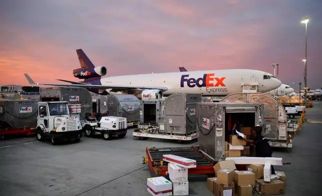 FILE - Brenda Thompson, right, loads packages into a container at the FedEx hub at Los Angeles International Airport, Dec. 2, 2013, in Los Angeles. (AP Photo/Jae C. Hong, File)