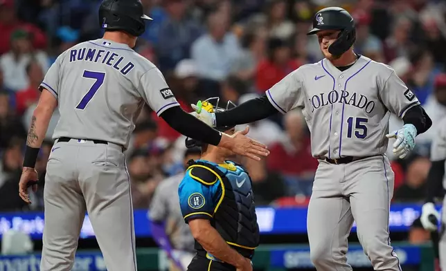 Colorado Rockies' Hunter Goodman (15) celebrates his two-run home run off of Philadelphia Phillies pitcher Jesús Luzardo, with teammate TJ Rumfield during the fourth inning of a baseball game, Friday, May 8, 2026, in Philadelphia. (AP Photo/Matt Rourke)