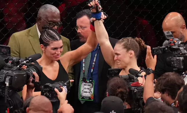 Gina Carano, of the United States, left, lifts the arm of Ronda Rousey, of the United States, after Rousey defeated Carano in their featherweight mixed martial arts fight Saturday, May 16, 2026, in Inglewood, Calif. (AP Photo/Jae C. Hong )