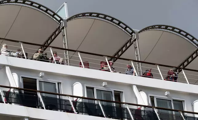 Passengers stand aboard the British cruise ship Ambition, as French authorities have ordered 1,700 passengers and crew to stay on board due to a gastrointestinal illness outbreak, in Bordeaux, southwestern France, Wednesday, May 13, 2026. (AP Photo/Caroline Blumberg)
