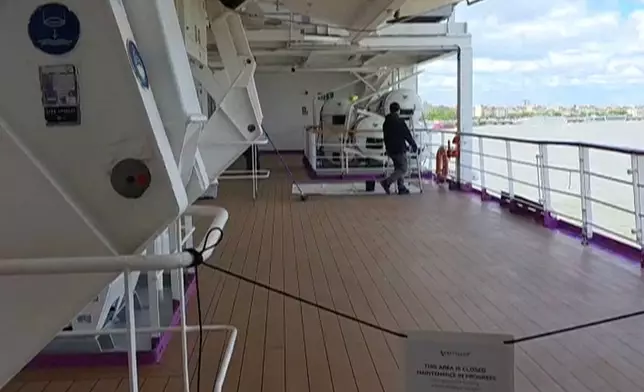 A man walks on a deck of the British cruise ship the Ambition after 1,700 passengers and crew were ordered to remain on board after an outbreak of gastrointestinal illness, in the port of Bordeaux, France, Wednesday, May 13, 2026. (Kevin Starrs via AP)
