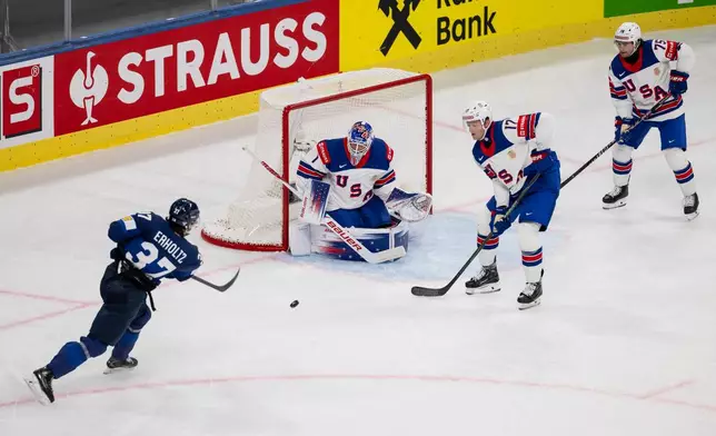 Finland's Eemil Erholtz, left, shoots on goal against USA's goaltender Devin Cooley, Will Borgen and Connor Clifton, right, during the Men's Ice Hockey World Championship preliminary round game between Finland and the USA in Zurich, Switzerland, Monday, May 18, 2026. (Andreas Becker/Keystone via AP)
