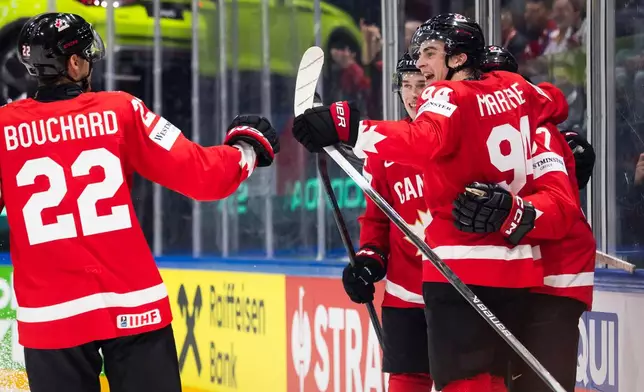 Canada's Porter Martone, right, celebrates with his teammates after scoring his side's first goal during the 2026 IIHF Men's Ice Hockey World Championship preliminary round group B game between Canada and Denmark, in Fribourg, Switzerland, Monday, May 18, 2026. (Peter Klaunzer/Keystone via AP)