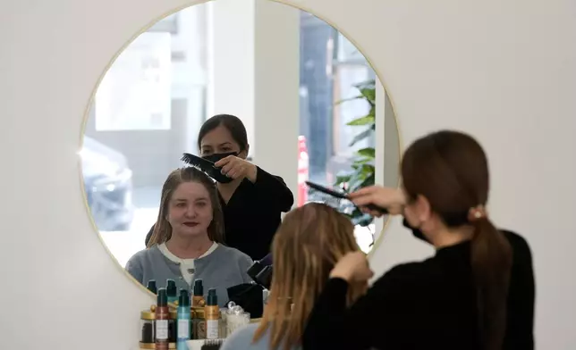 Head spa specialist Ha Truong, right, uses a Red and Blue light brush on Liz Evans to help with hair growth and reduce bacteria while massaging the scalp to help the scalp serum absorb during a treatment at Sunday Headspa Thursday, April 16, 2026, in San Francisco. (AP Photo/Jeff Chiu)