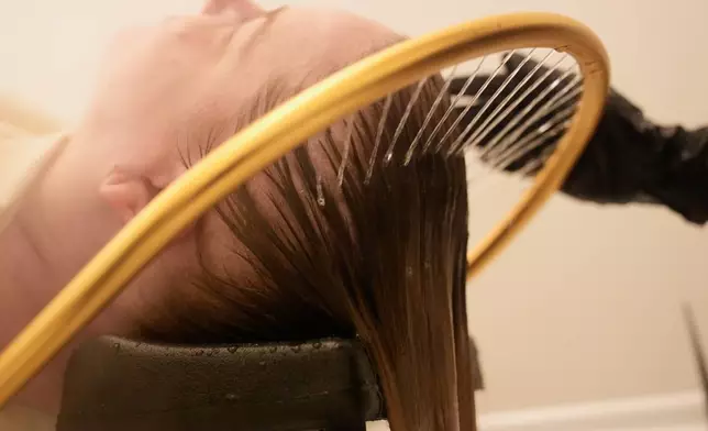 Head spa specialist Ha Truong applies a halo waterfall device to Liz Evans, left, during a treatment at Sunday Headspa Thursday, April 16, 2026, in San Francisco. (AP Photo/Jeff Chiu)