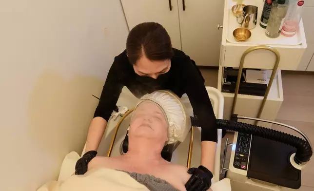 Liz Evans, bottom, wears a warm misting cap, which produces nano mist that hydrates the scalp and hair, as head spa specialist Ha Truong performs a treatment at Sunday Headspa Thursday, April 16, 2026, in San Francisco. (AP Photo/Jeff Chiu)
