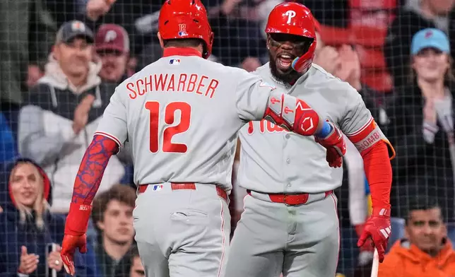 Philadelphia Phillies' Kyle Schwarber (12) is congratulated by Adolis García after his two-run home run during the eighth inning of a baseball game against the Boston Red Sox, Thursday, May 14, 2026, in Boston. (AP Photo/Charles Krupa)