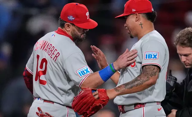Philadelphia Phillies left fielder Kyle Schwarber (12) celebrates with pitcher Jhoan Duran after defeating the Boston Red Sox following a baseball game, Thursday, May 14, 2026, in Boston. (AP Photo/Charles Krupa)
